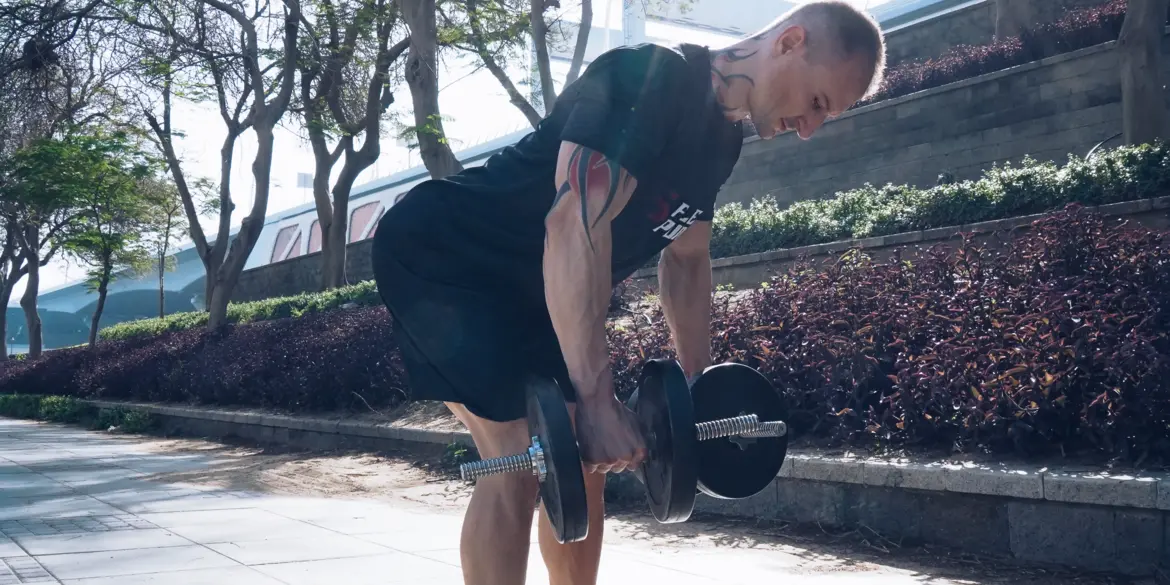 A closeup of FlexAndPunch fitness trainer Cleber Marcolan displaying dumbbell bent over biceps curl